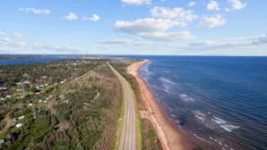 Luchtbeeld van een kustweg met een strand aan de ene kant en een bebost gebied aan de andere kant.