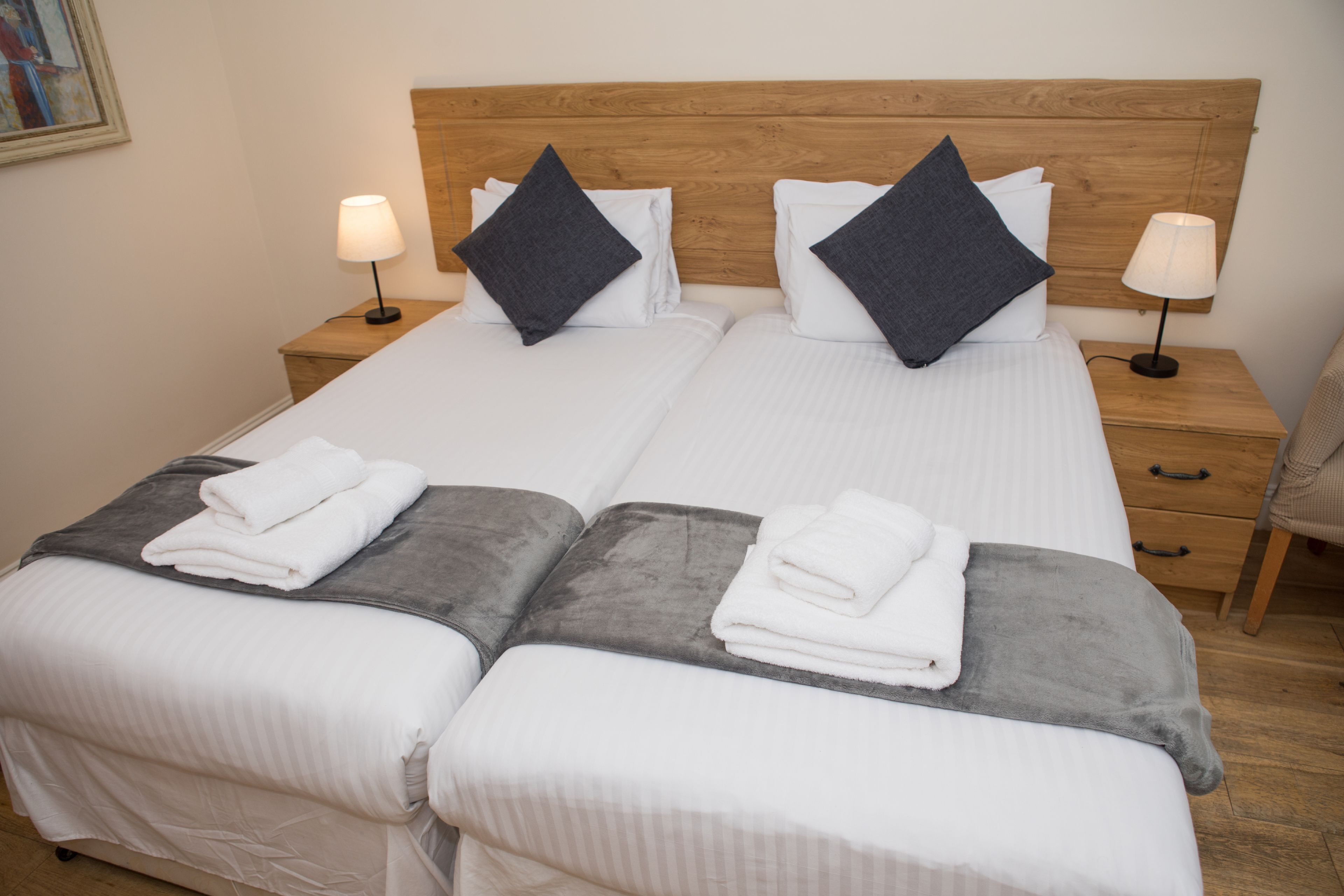 Una cama doble con dos almohadas, una mesita de noche con lámpara y una silla.