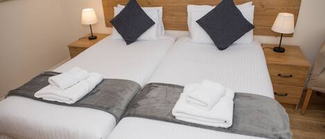 Una cama doble con dos almohadas, una mesita de noche con lámpara y una silla.
