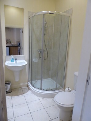 Une salle de bain avec une douche à parois de verre, un lavabo et des toilettes.