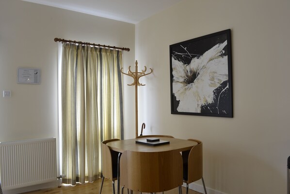 A room with a round wooden table, a coat rack, a radiator, and a large abstract painting on the wall.