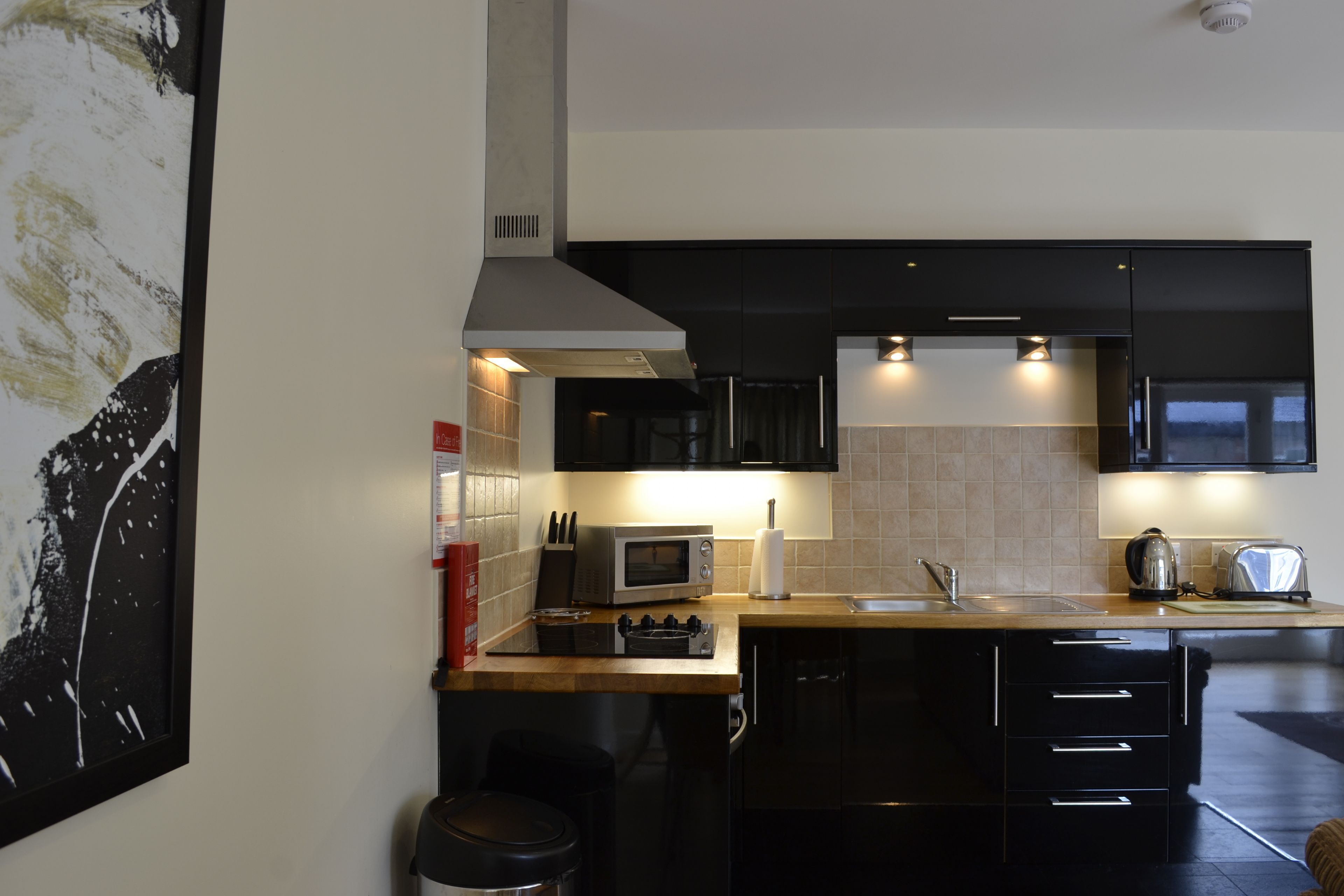 Een moderne keuken met zwarte kastjes, een magnetron, een fornuis en een spoelbak.