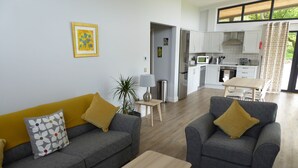 A modern living room with two grey sofas, a wooden coffee table, and a dining area with a white table and chairs. - Oak Lodge (Auchendennan) - sleeps 4 guests  in 2 bedrooms (Alexandria)