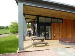 A covered outdoor area with a wooden deck, a table, and a bench. - Oak Lodge (Auchendennan) - sleeps 4 guests  in 2 bedrooms (Alexandria)