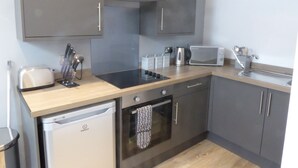 A modern kitchen with grey cabinets, a built-in oven, a microwave, and a dishwasher. - The Stables Upper Cottage 7 (Auchendennan) - sleeps 2 guests  in 0 bedrooms (Alexandria)