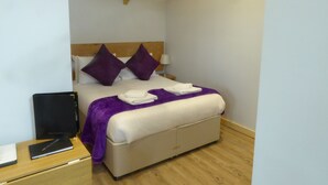 A bedroom with a bed, wooden headboard, white walls, and a wooden floor. - The Stables Upper Cottage 7 (Auchendennan) - sleeps 2 guests  in 0 bedrooms (Alexandria)