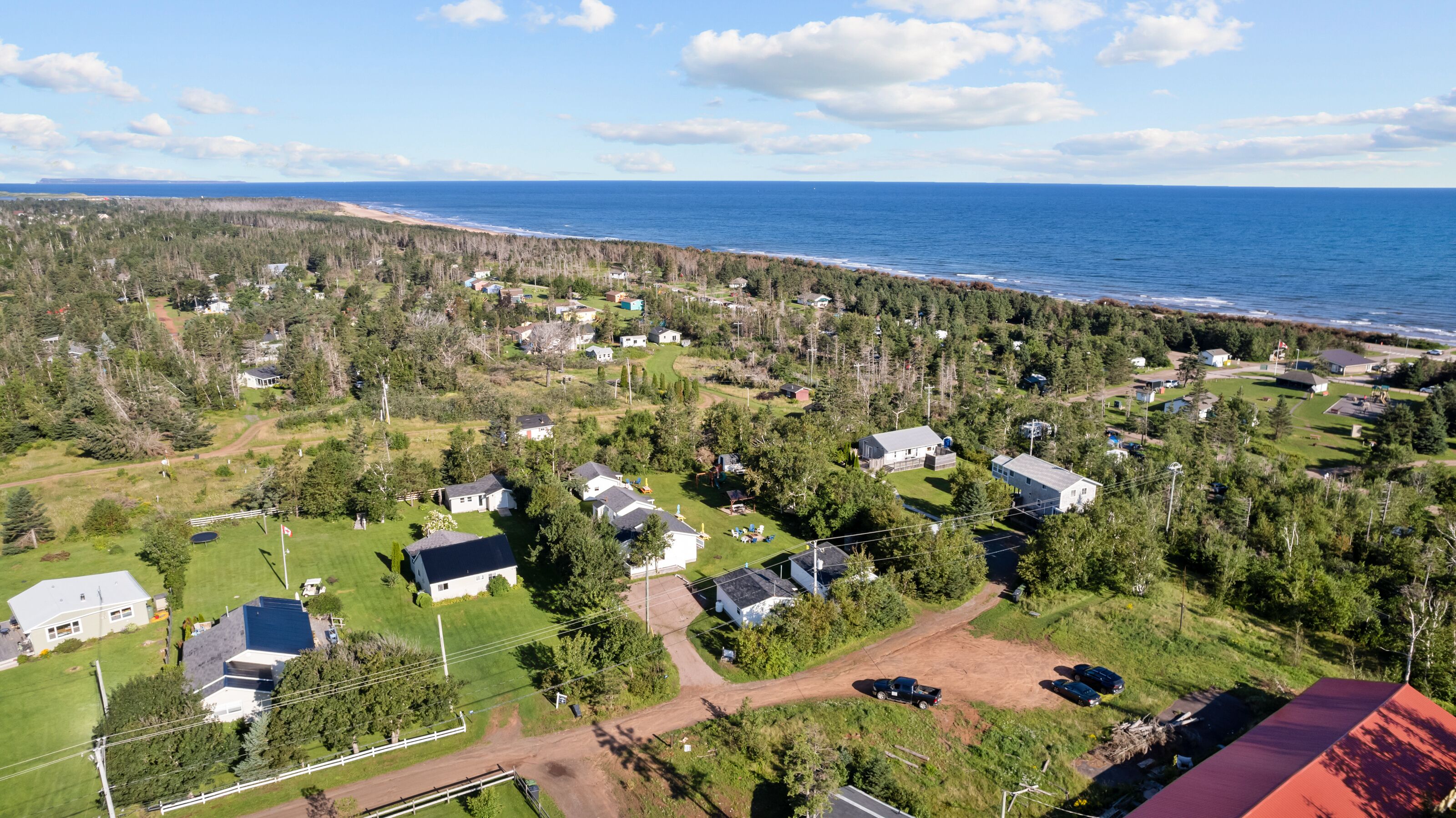 Vue aérienne d’une zone résidentielle côtière, avec des maisons, des routes et une plage.