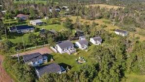 An aerial view of a residential area with multiple houses, green lawns, and a fenced property. - Sand Dune Cottage, 2 BRs, Kitchen, living and a patio (York)