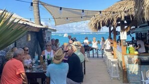 A wooden deck with tables and chairs, overlooking the ocean. - Cozy 1 BR apartment with AC and WiFi, walking distance to the beach in Bavaro (Punta Cana)