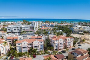 A coastal resort area with multi-story buildings, palm trees, and a view of the ocean. - Cozy 1 BR apartment with AC and WiFi, walking distance to the beach in Bavaro (Punta Cana)