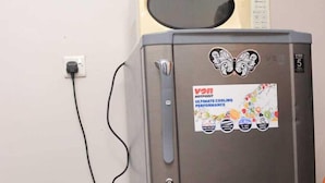 A stainless steel refrigerator with a microwave on top, a power cord, and a potted plant beside it. - Beautiful 1-Bed Apartment in Nairobi (Nairobi)