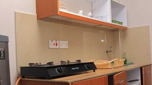 A compact kitchenette with a gas stove, a blue gas cylinder, and a small sink. - Beautiful 1-Bed Apartment in Nairobi (Nairobi)