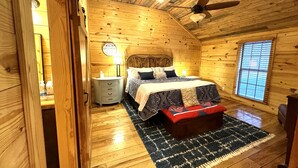 A cozy wooden cabin bedroom with a bed, nightstand, and a window.