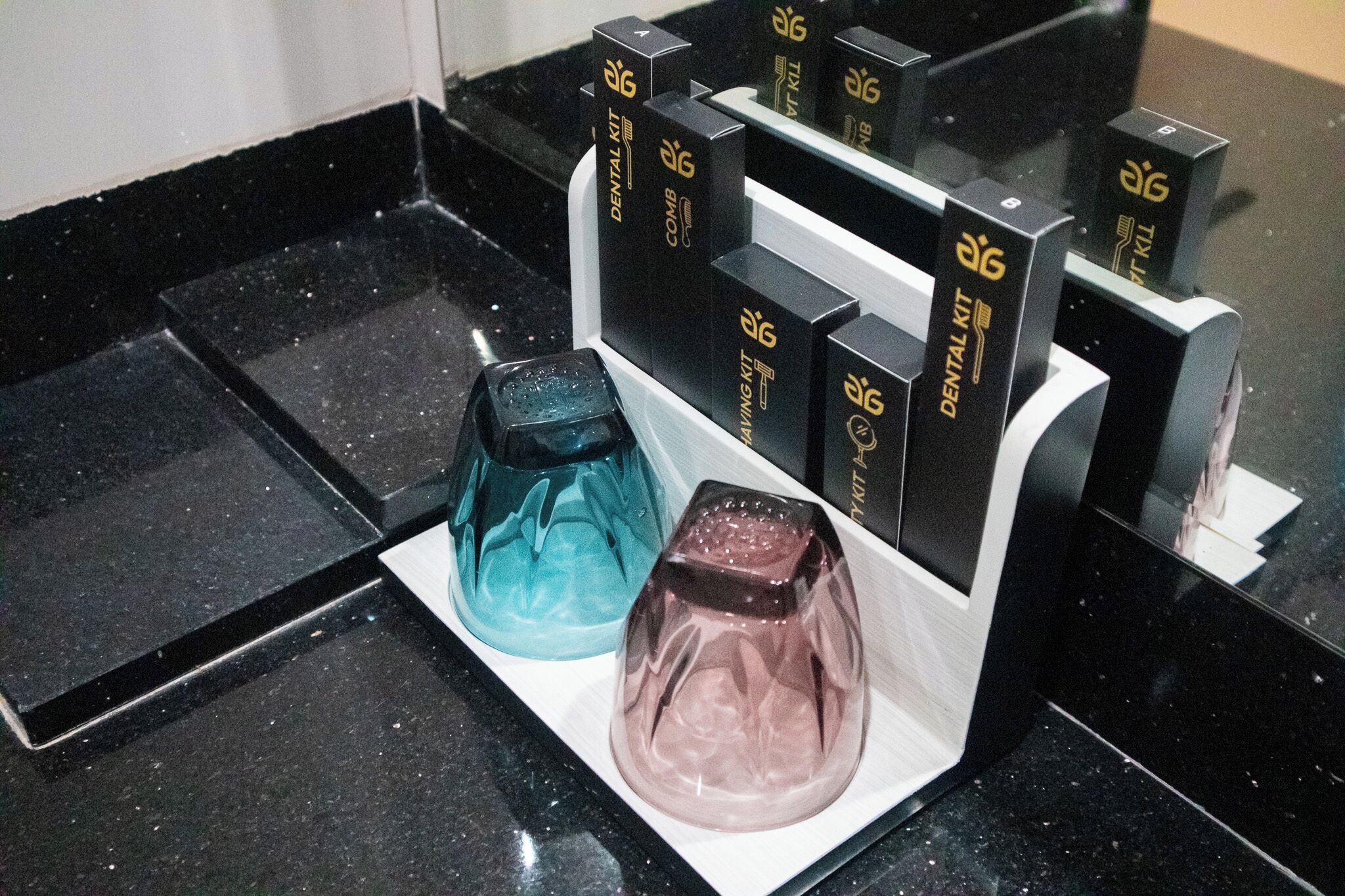 A dental care station with a black countertop and a white tray holding a dental kit and two containers.