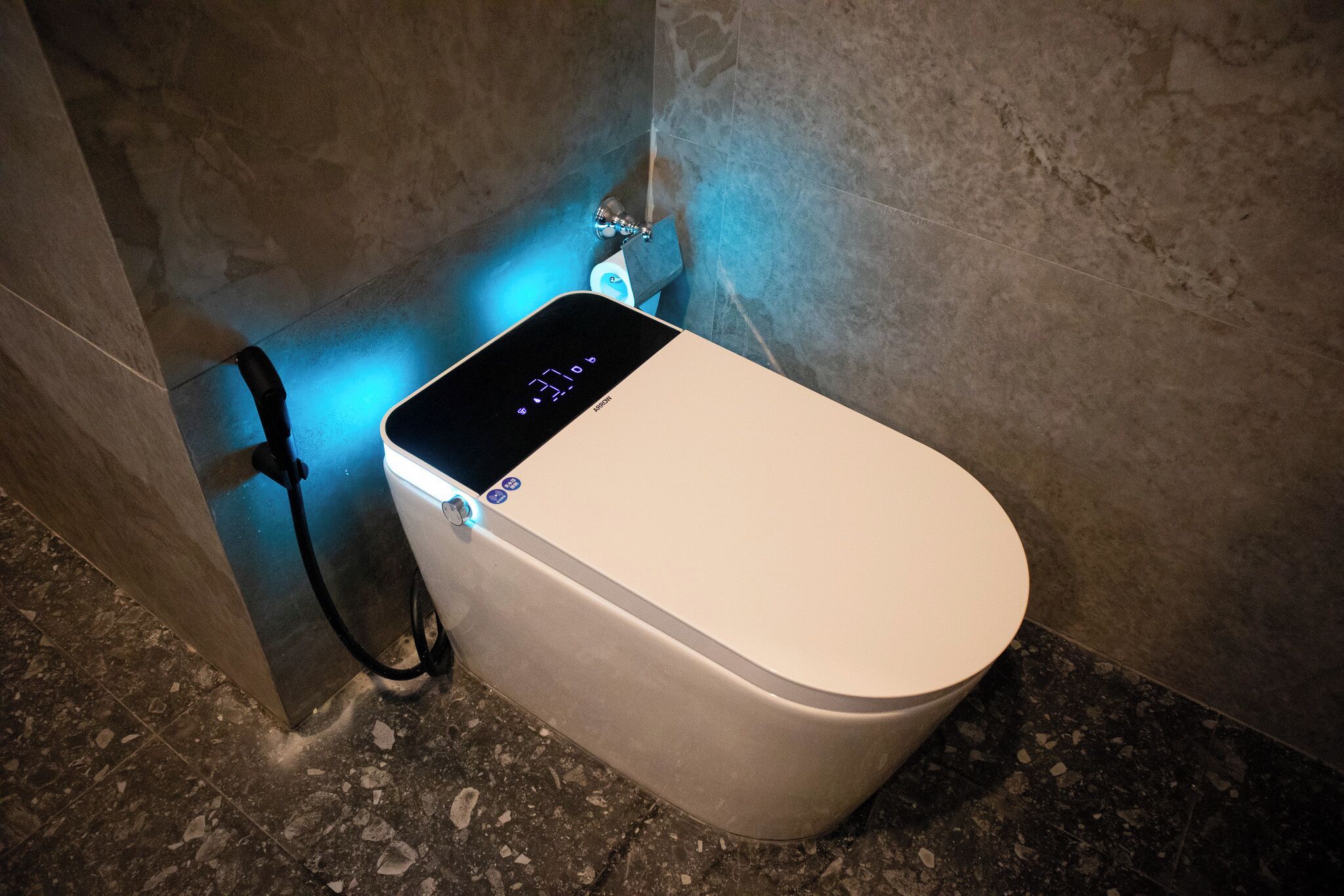 A modern toilet with a digital display and a power cord plugged in.