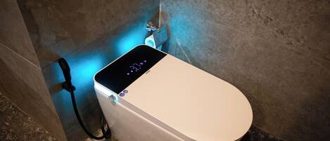 A modern toilet with a digital display and a power cord plugged in.