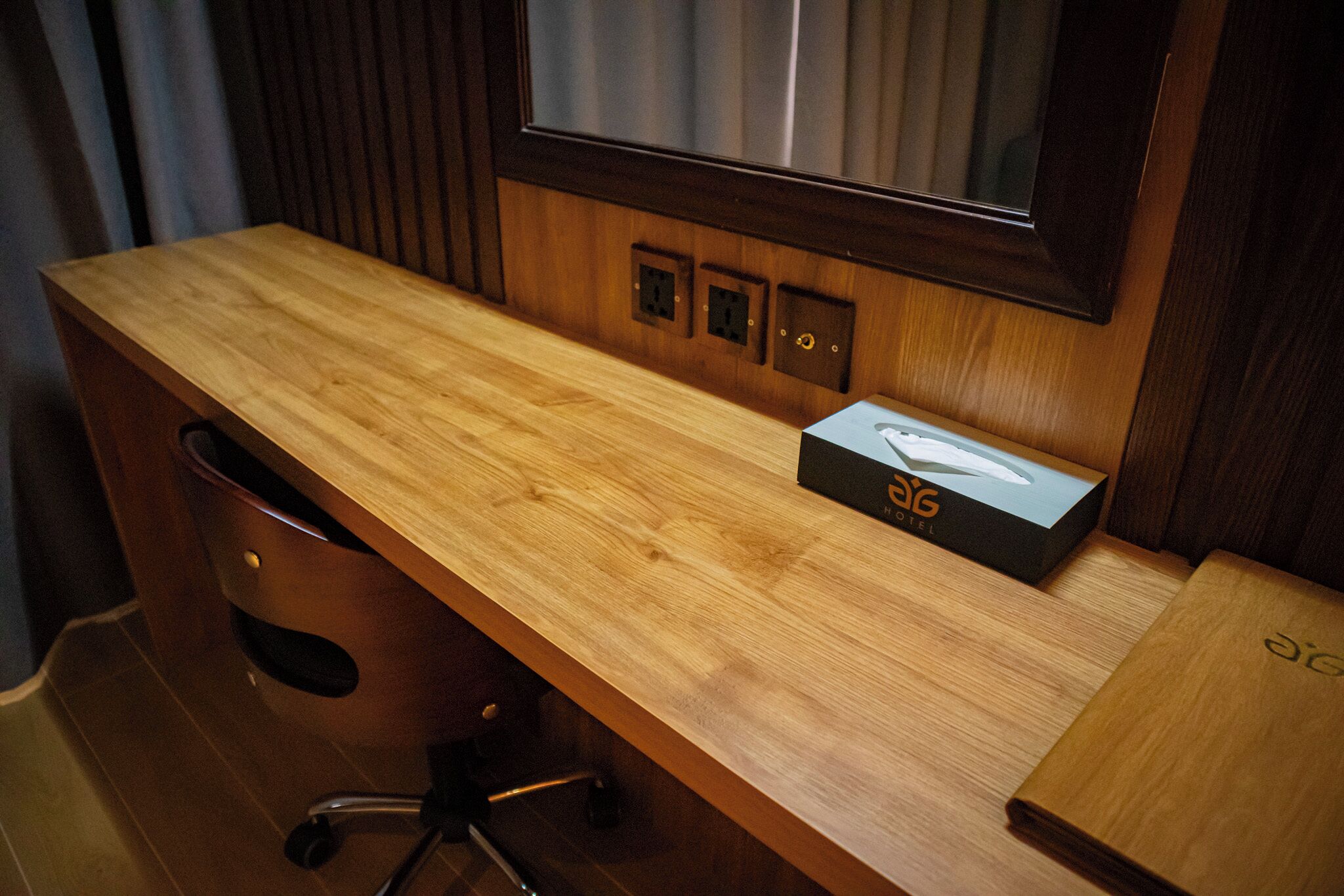 A wooden desk with a box labeled "AIG" and a mirror above it.