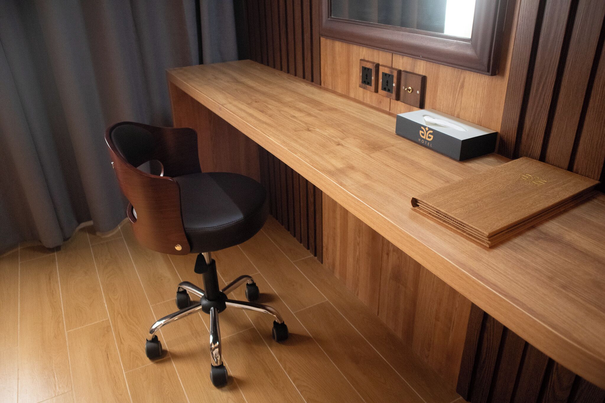 Una scrivania in legno con una sedia da ufficio nera, un portatovaglioli e una pila di libri.