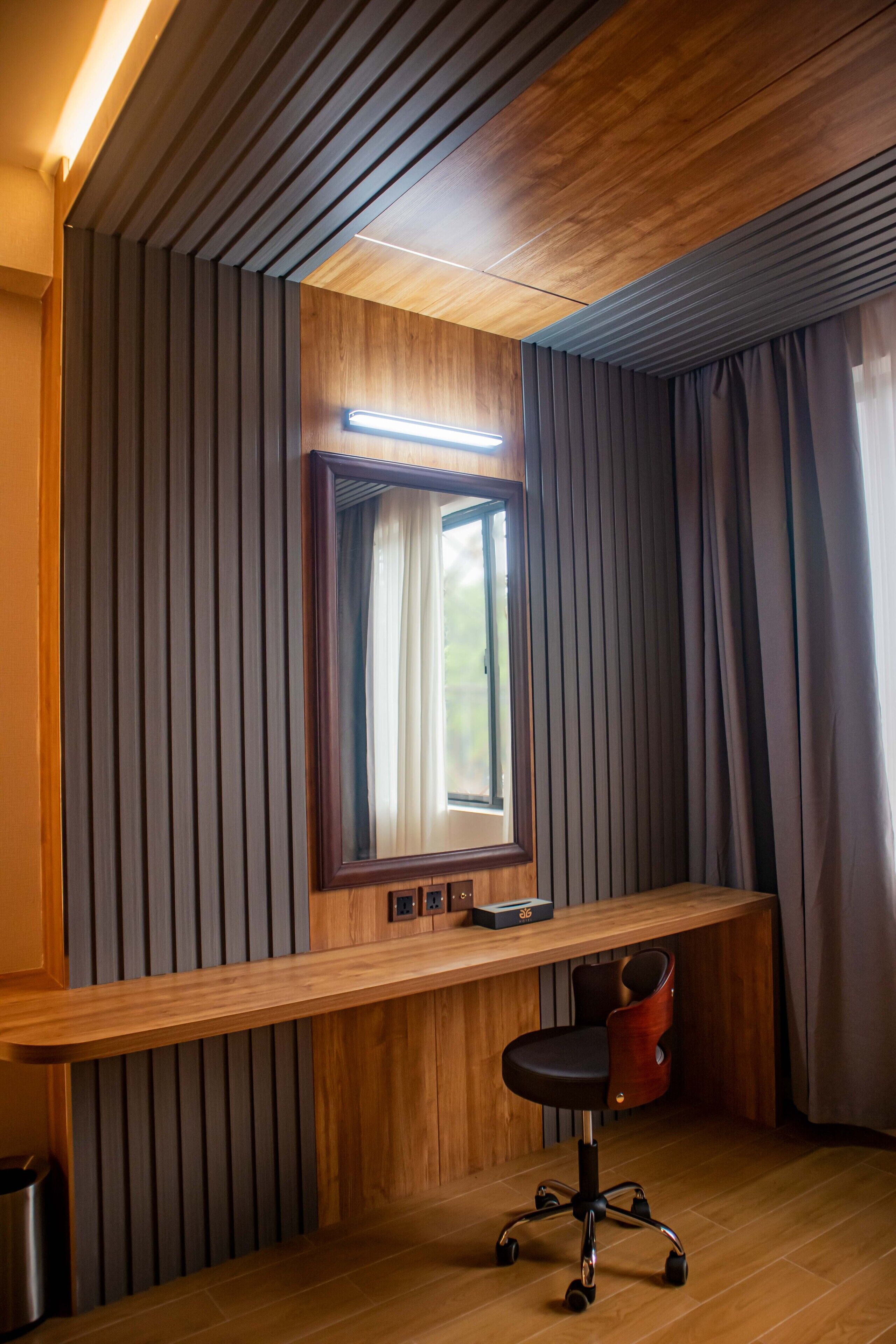 A modern room with a wooden desk, a mirror, and a chair.
