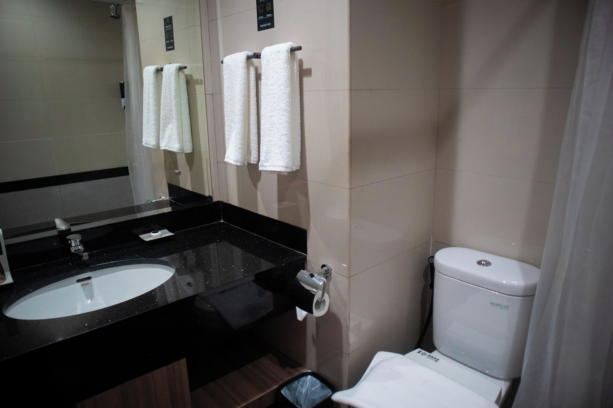 A bathroom with a black countertop sink, a toilet, and two towels hanging on a rack.