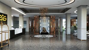 Een moderne hotellobby met een centraal decoratief element, een receptiebalie en een gouden trolley.