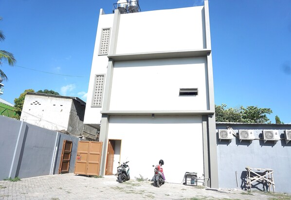 Um edifício moderno com telhado plano e porta de garagem, com duas motocicletas estacionadas em frente.