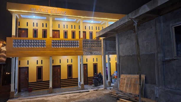 Un edificio de varios pisos con fachada amarilla y múltiples puertas, algunas de las cuales están numeradas.