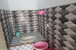Un baño con piso de diseño escocés, un lavabo y un lavamanos rosa, además de una escoba.