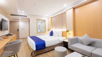 A hotel room with a bed, a sofa, a desk, and a television.