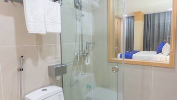 Un baño moderno con ducha de vidrio, inodoro y toallero con toallas dobladas.