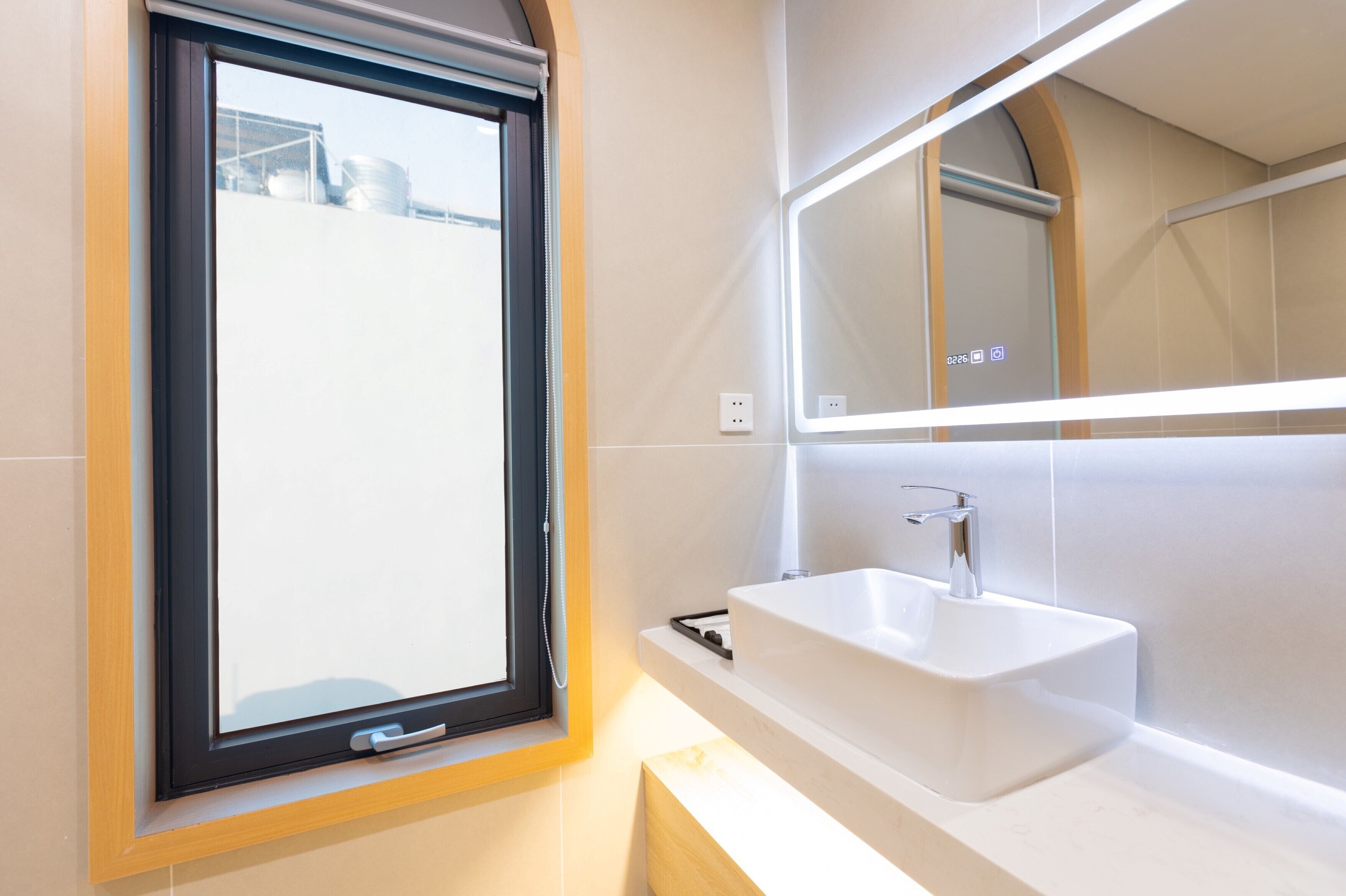 Un bany modern amb una finestra gran, un lavabo blanc i un mirall.
