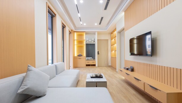 Una sala de estar moderna con sofá, mesa de centro, televisor y paneles de madera.