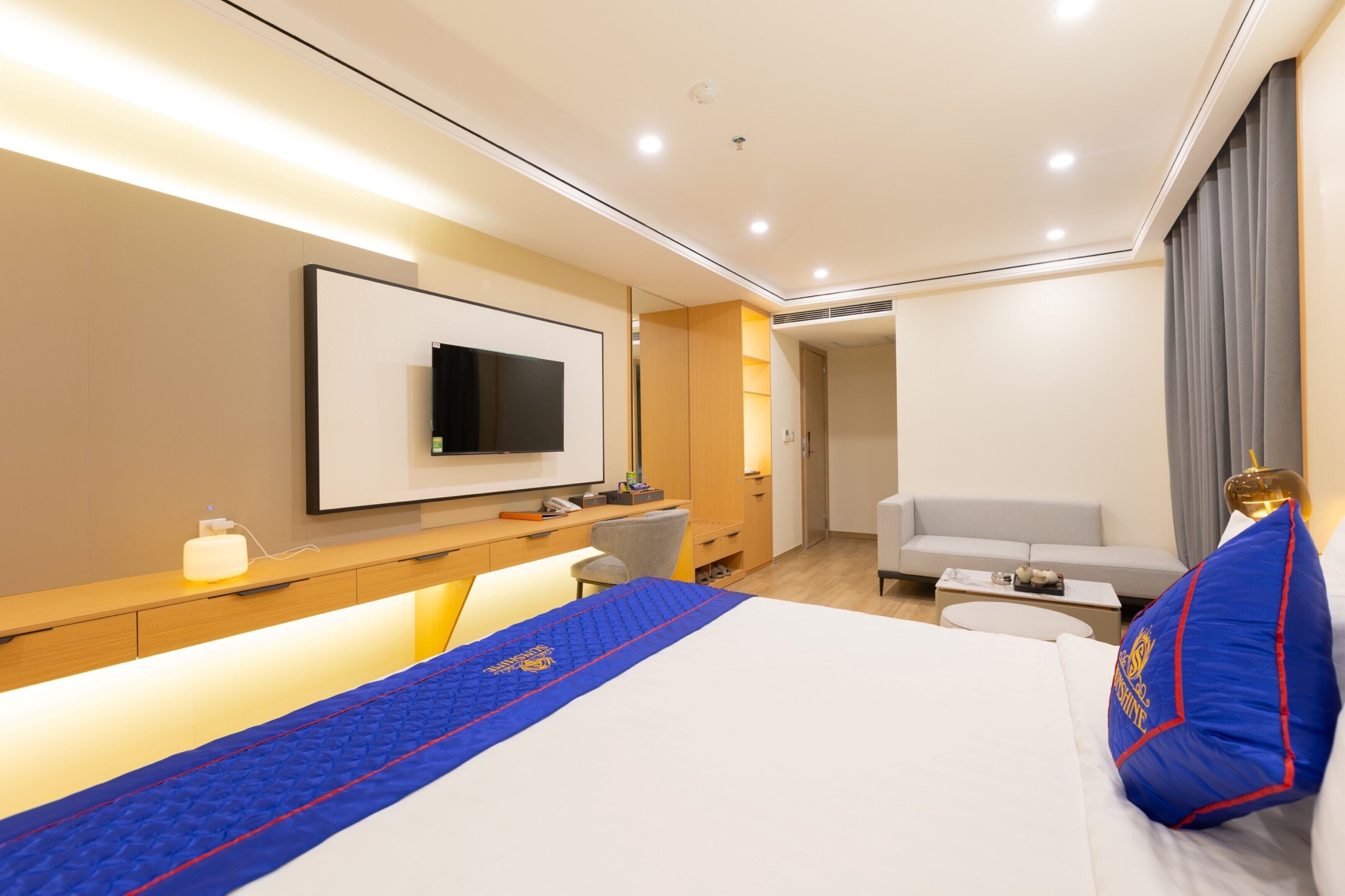 Une chambre d’hôtel moderne équipée d’un lit, d’un bureau, d’une télévision et d’un canapé.