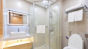 Un baño moderno con ducha de vidrio, un lavabo blanco y un inodoro.