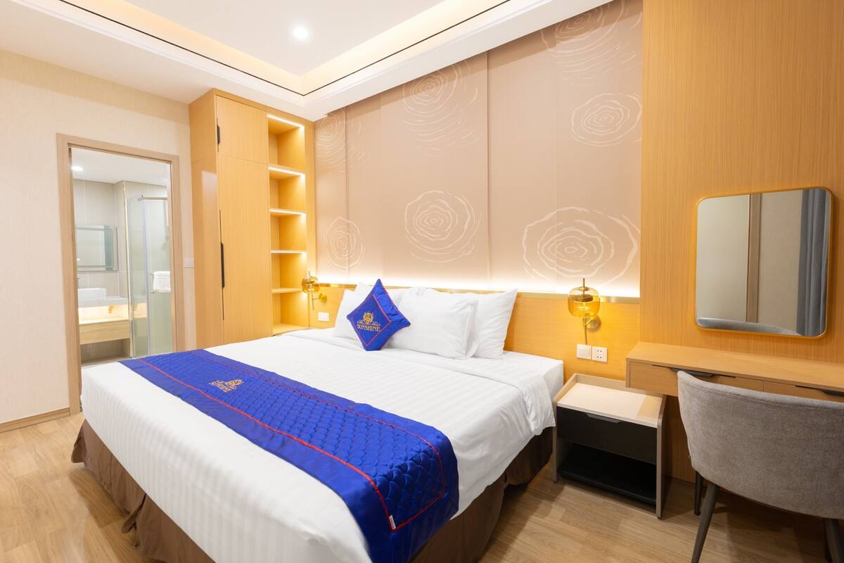Ein Hotelzimmer mit einem großen Bett, einem Schreibtisch, einem Sessel, einem Spiegel und einem Kleiderschrank.