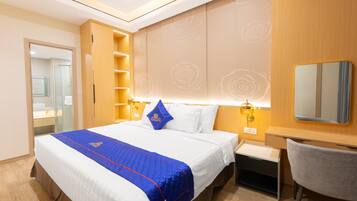 A hotel room with a large bed, a desk, a chair, a mirror, and a wardrobe.