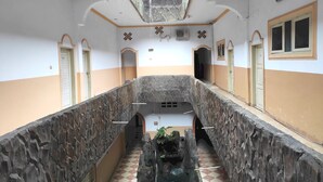 A corridor with a stone wall, a central water feature, and multiple doors. - Hotel O Pondok Bintang (Kendari)