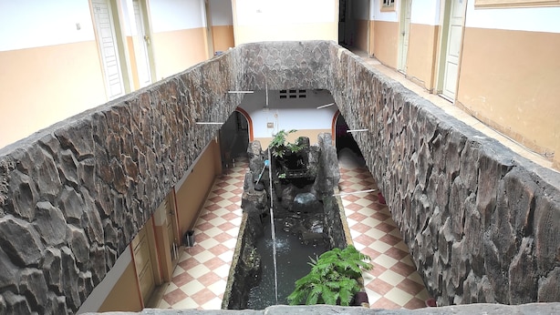 A corridor with a central water feature, stone walls, and a checkered floor. - Hotel O Pondok Bintang (Kendari)