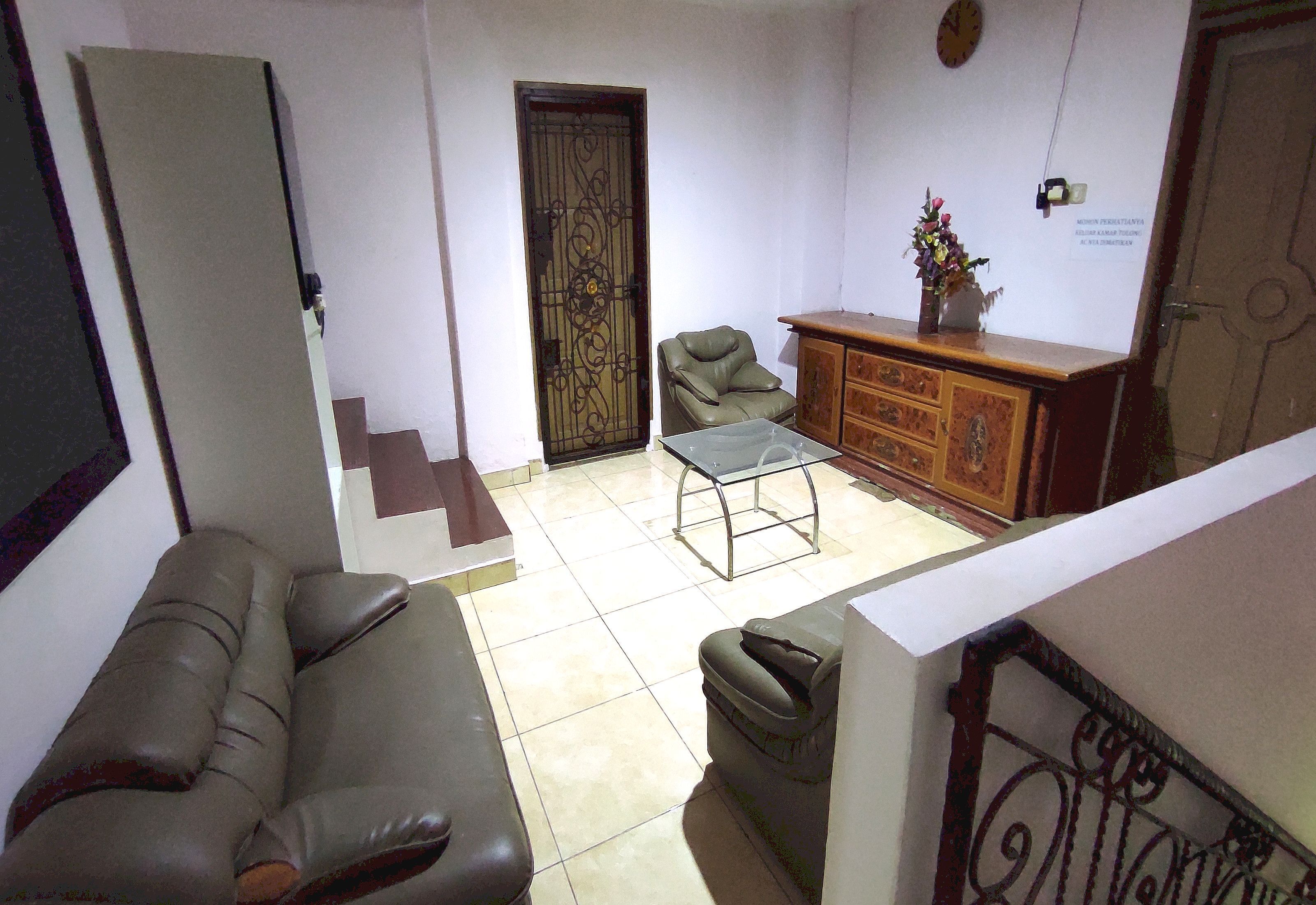 Una sala de estar con sofá, sillón, aparador y una puerta.