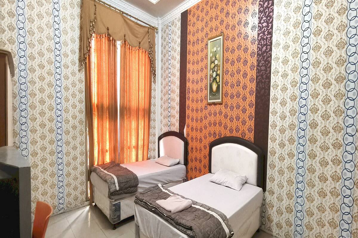 A hotel room with two single beds, a desk, and a chair.
