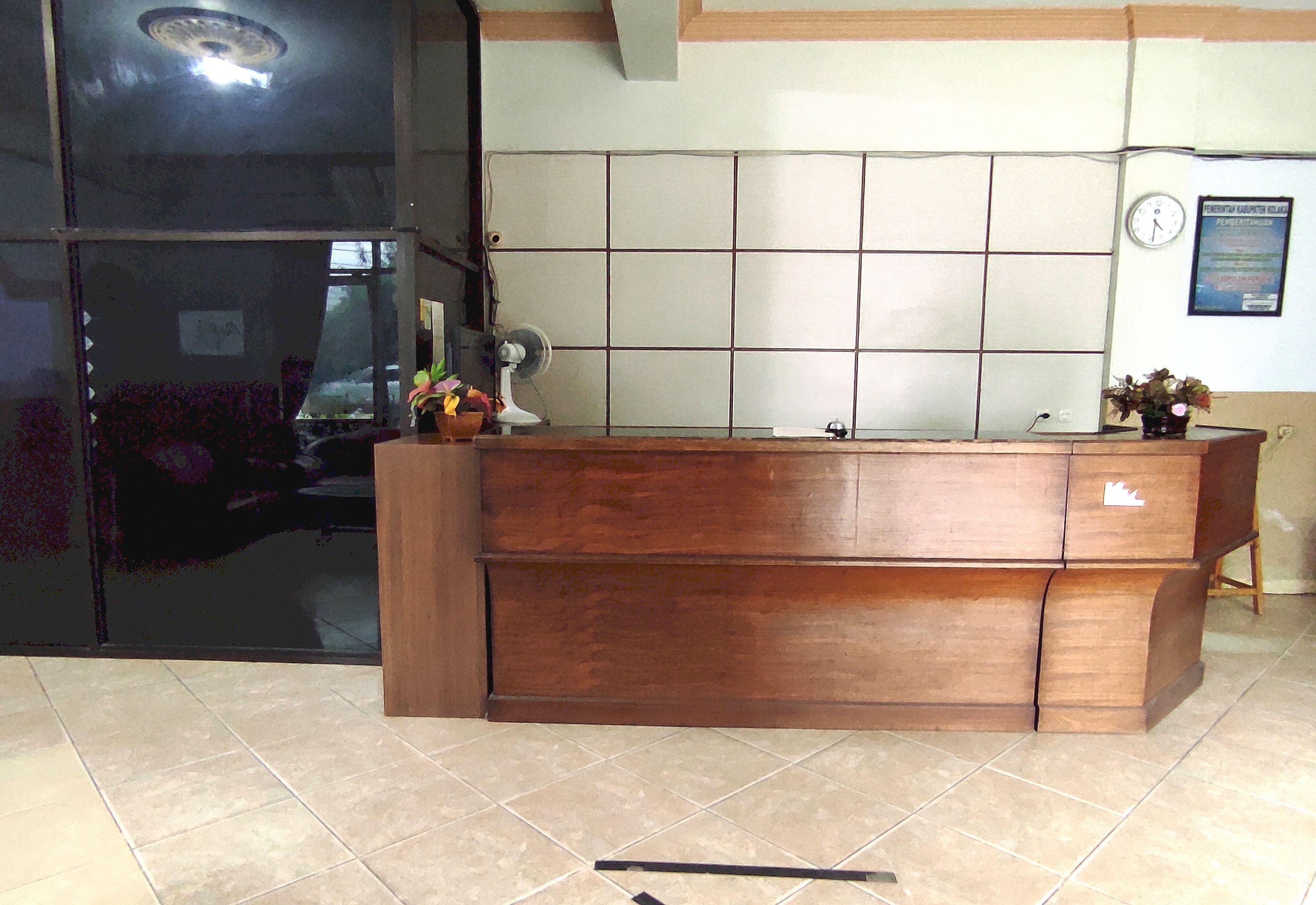 A reception desk with a tiled wall behind it, a clock, and a poster on the wall.