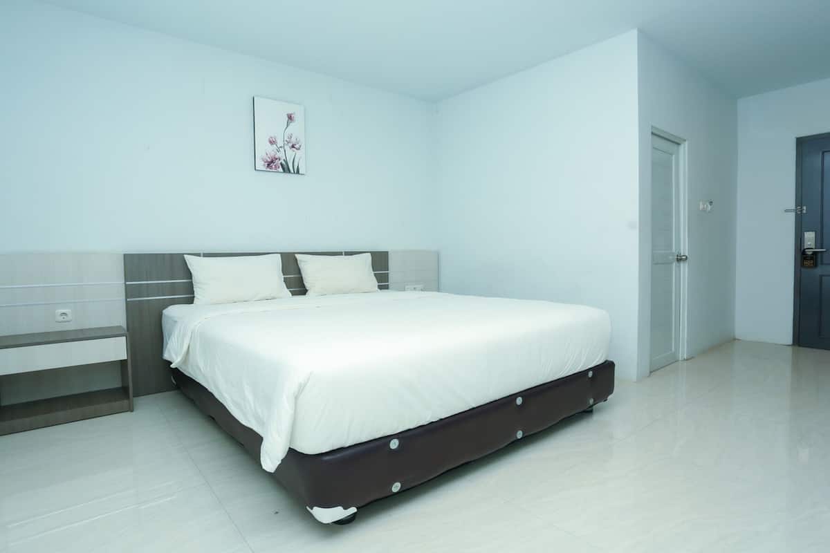 A modern bedroom with a large bed, a bedside table, and a door.