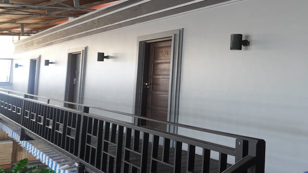 A building exterior with a covered walkway, metal railings, and doors marked with numbers. - OYO 93774 Khaira Kos Dan PenginapanNearYani Heahlerr (Marabahan)