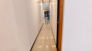 A long, narrow hallway with a shiny tiled floor and white walls. - Hotel O Nilam Guest HouseNearYani Heahlerr (Marabahan)