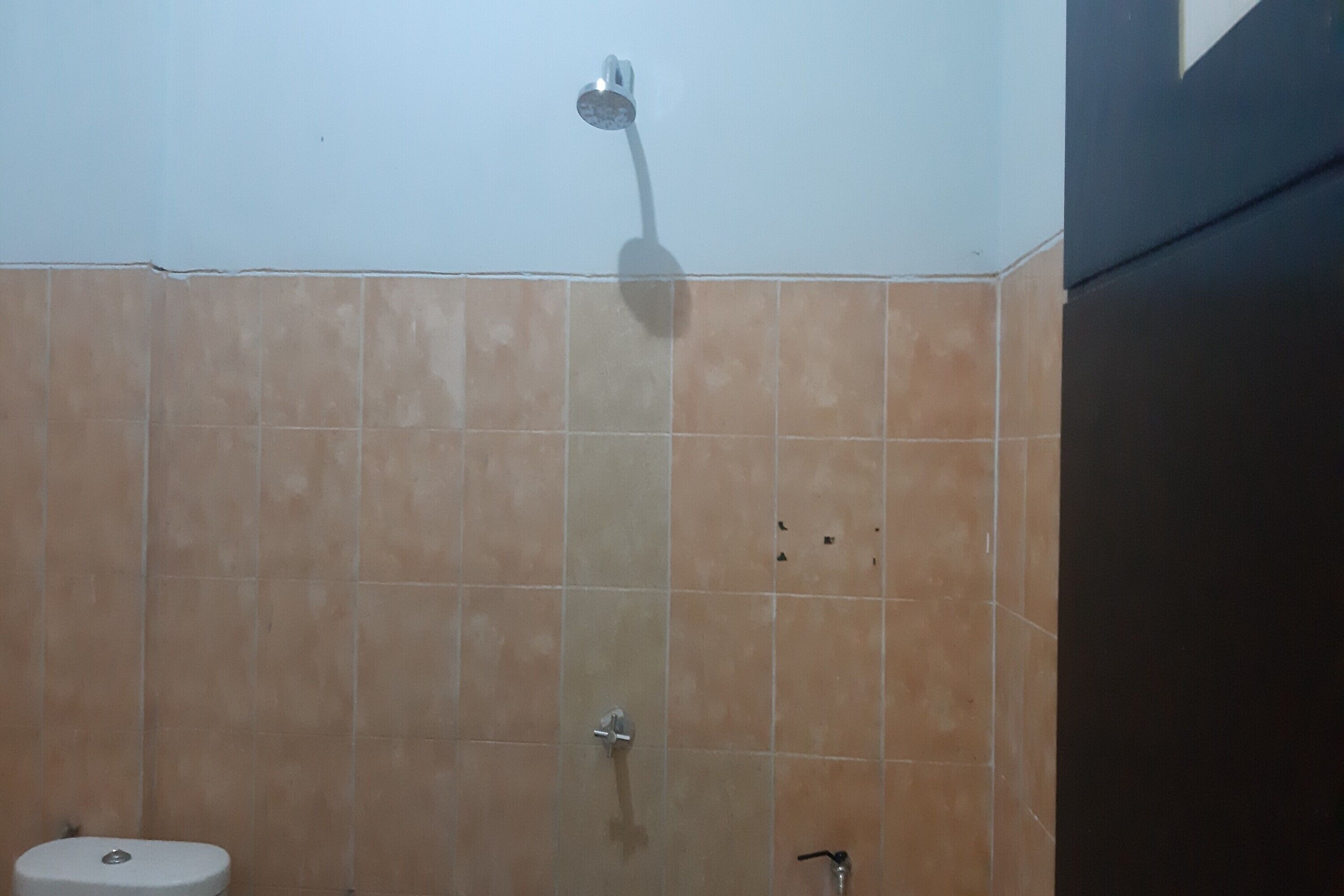 A bathroom with beige tiles, a shower, and a toilet.