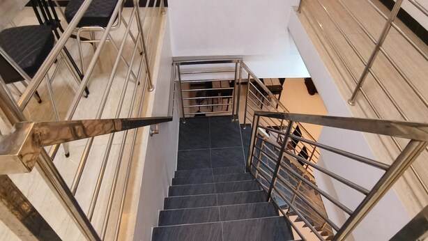 A staircase with metal railings and dark tiled steps leading upwards. - Hotel O Nilam Guest HouseNearYani Heahlerr (Marabahan)