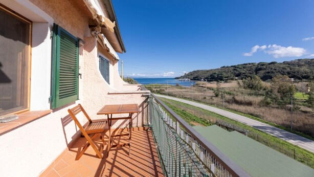 Een balkon met uitzicht op zee en heuvels.