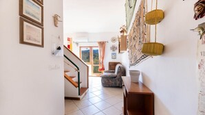 Een gang met een trap, een gestreept fauteuil en een wand met decoratieve objecten.