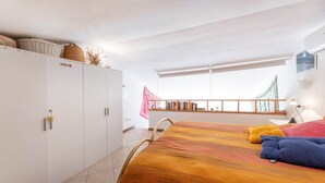 Een slaapkamer met een bed, een kledingkast, een raam met uitzicht en een balkon.