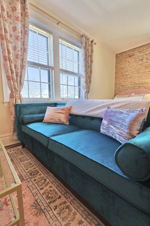 Relax in this inviting room with a sofa, floral curtains, and a patterned rug.